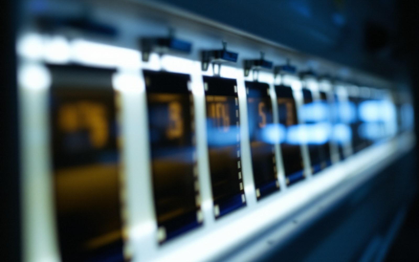 A row of films clipped to a backlit viewing box in a darkened reading room